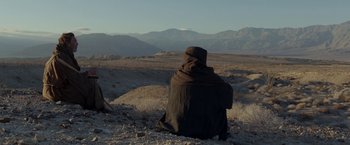 Movie still from “Last Days in the Desert” (2015), directed by Rodrigo García – A person in a hooded cloak sitting on the ground; Extreme Wide shot, Low angle