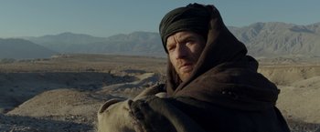 Movie still from “Last Days in the Desert” (2015), directed by Rodrigo García – A man with a beard wrapped in a blanket in the desert; Close Up shot, Low angle