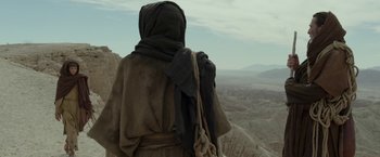 Movie still from “Last Days in the Desert” (2015), directed by Rodrigo García – A person in a robe and a scarf on a mountain; Wide shot, Low angle