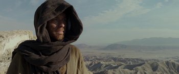 Movie still from “Last Days in the Desert” (2015), directed by Rodrigo García – A man with a beard wearing a hooded robe; Medium shot, Low angle