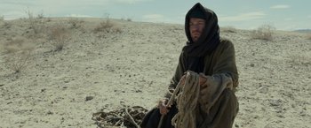 Movie still from “Last Days in the Desert” (2015), directed by Rodrigo García – A man sitting on the ground in the middle of the desert; Medium shot, Low angle