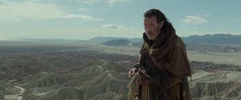 Movie still from “Last Days in the Desert” (2015), directed by Rodrigo García – A man standing on top of a mountain holding a rope; Medium shot, Low angle