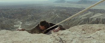 Movie still from “Last Days in the Desert” (2015), directed by Rodrigo García – A man climbing up the side of a mountain with a rope; Wide shot, Overhead angle