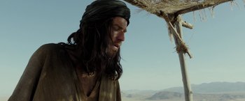 Movie still from “Last Days in the Desert” (2015), directed by Rodrigo García – A man with long black hair and a black beard; Close Up shot, Low angle