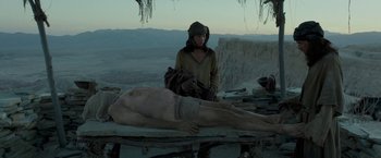Movie still from “Last Days in the Desert” (2015), directed by Rodrigo García – A man sitting next to a dead body in the desert; Wide shot, Low angle