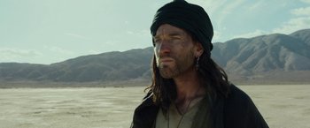Movie still from “Last Days in the Desert” (2015), directed by Rodrigo García – A man with long black hair and a green turban; Close Up shot, Over the shoulder angle