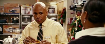 Movie still from “Last Holiday” (2006), directed by Wayne Wang – A man in a yellow dress shirt and tie eating a donut; Close Up shot, Over the shoulder angle