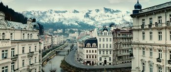 Movie still from “Last Holiday” (2006), directed by Wayne Wang – A view of a city with snow capped mountains in the background; Extreme Wide shot, High angle