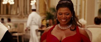 Movie still from “Last Holiday” (2006), directed by Wayne Wang – A woman in a red dress smiling for the camera; Close Up shot, Over the shoulder angle