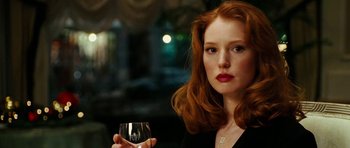 Movie still from “Last Holiday” (2006), directed by Wayne Wang – A beautiful woman with red hair holding a glass of wine; Close Up shot, Over the shoulder angle