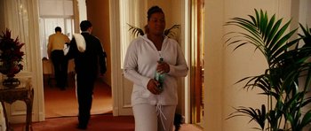 Movie still from “Last Holiday” (2006), directed by Wayne Wang – A woman holding a water bottle while standing in a hallway; Medium shot, Over the shoulder angle