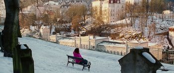 Movie still from “Last Holiday” (2006), directed by Wayne Wang – A woman sitting on a bench in the snow; Extreme Wide shot, High angle