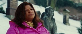 Movie still from “Last Holiday” (2006), directed by Wayne Wang – A woman in a pink jacket is standing in front of a statue; Close Up shot, Low angle