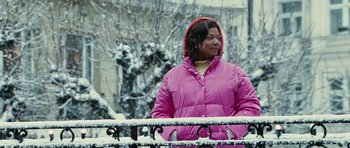 Movie still from “Last Holiday” (2006), directed by Wayne Wang – A woman in a pink jacket standing next to a railing in the snow; Medium shot, Low angle