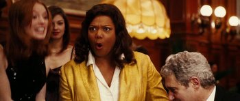 Movie still from “Last Holiday” (2006), directed by Wayne Wang – A woman in a yellow jacket is making a funny face; Close Up shot, Over the shoulder angle
