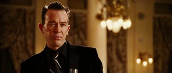 Movie still from “Last Holiday” (2006), directed by Wayne Wang – A person wearing a suit holding a wine glass; Close Up shot, Low angle