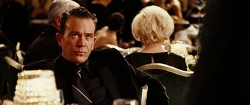 Movie still from “Last Holiday” (2006), directed by Wayne Wang – A man in a suit sitting in front of other people; Close Up shot, Over the shoulder angle