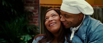 Movie still from “Last Holiday” (2006), directed by Wayne Wang – A man and a woman are smiling for the camera; Close Up shot, Over the shoulder angle