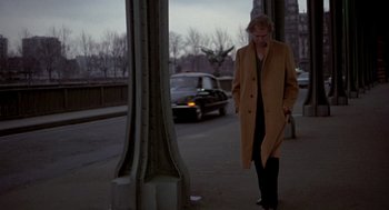 Movie still from “Last Tango in Paris” (1972), directed by Bernardo Bertolucci – A man walking on a sidewalk near a street; Wide shot, Low angle