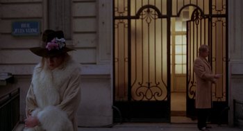 Movie still from “Last Tango in Paris” (1972), directed by Bernardo Bertolucci – A woman wearing a hat and a white coat walking down the street; Wide shot, Over the shoulder angle