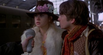 Movie still from “Last Tango in Paris” (1972), directed by Bernardo Bertolucci – A woman wearing a hat is holding a microphone and a man wearing a hat is holding a microphone; Close Up shot, Over the shoulder angle