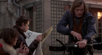 Movie still from “Last Tango in Paris” (1972), directed by Bernardo Bertolucci – Two men sitting on a bike looking at a newspaper; Medium shot, Over the shoulder angle