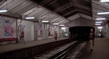 Movie still from “Last Tango in Paris” (1972), directed by Bernardo Bertolucci – A person standing on a train platform next to train tracks; Extreme Wide shot, High angle