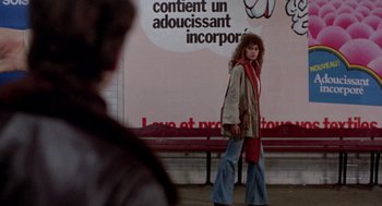 Movie still from “Last Tango in Paris” (1972), directed by Bernardo Bertolucci – A woman is walking down the sidewalk in front of a building; Wide shot, Over the shoulder angle