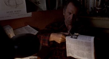 Movie still from “Last Tango in Paris” (1972), directed by Bernardo Bertolucci – A man sitting at a table reading a newspaper; Medium shot, High angle