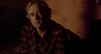 Movie still from “Last Tango in Paris” (1972), directed by Bernardo Bertolucci – A man in a red and black plaid robe; Close Up shot, Over the shoulder angle