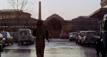 Movie still from “Last Tango in Paris” (1972), directed by Bernardo Bertolucci – A person walking down a street with an umbrella; Wide shot, Low angle