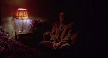 Movie still from “Last Tango in Paris” (1972), directed by Bernardo Bertolucci – A man sitting in a chair in a dark room; Medium shot, High angle