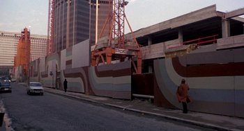 Movie still from “Last Tango in Paris” (1972), directed by Bernardo Bertolucci – A man walking down a street near a building; Extreme Wide shot, High angle