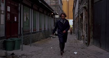 Movie still from “Last Tango in Paris” (1972), directed by Bernardo Bertolucci – A man walking down the street in a black coat; Wide shot, Low angle