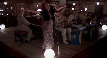 Movie still from “Last Tango in Paris” (1972), directed by Bernardo Bertolucci – A woman standing on a stage in front of a microphone; Wide shot, Low angle