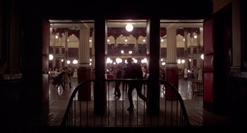 Movie still from “Last Tango in Paris” (1972), directed by Bernardo Bertolucci – People are walking in a large room at night; Extreme Wide shot, High angle