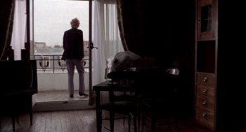 Movie still from “Last Tango in Paris” (1972), directed by Bernardo Bertolucci – A person standing in a room looking out of a window; Wide shot, Low angle