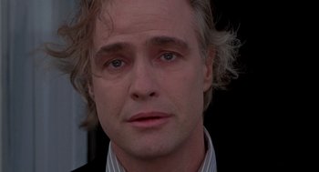 Movie still from “Last Tango in Paris” (1972), directed by Bernardo Bertolucci – A person wearing a suit and tie; Close Up shot, Low angle