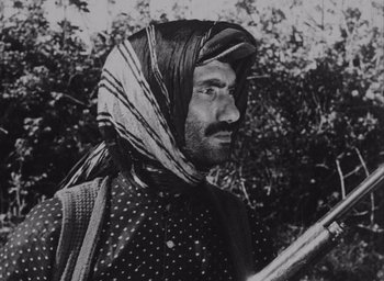 Movie still from “Law of the Border” (1966), directed by Lütfi Akad – A man with a beard and a turban on a field; Close Up shot, Low angle
