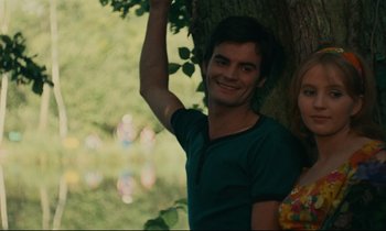Movie still from “Happiness” (1965), directed by Agnès Varda – A man and a woman standing next to a tree; Medium shot, Low angle