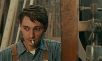 Movie still from “Happiness” (1965), directed by Agnès Varda – A young man smoking a cigarette while wearing an overalls; Close Up shot, Over the shoulder angle