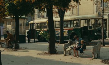 Movie still from “Happiness” (1965), directed by Agnès Varda – A woman sitting on a park bench with a small child; Wide shot, High angle