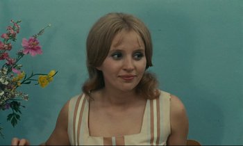 Movie still from “Happiness” (1965), directed by Agnès Varda – A young woman with long brown hair wearing a white dress; Close Up shot, Over the shoulder angle