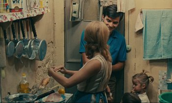Movie still from “Happiness” (1965), directed by Agnès Varda – A man and a woman in a kitchen with a child; Medium shot, High angle