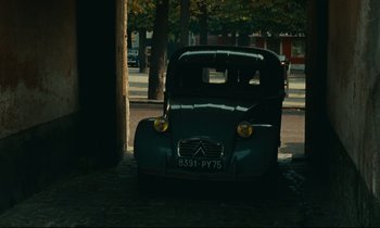 Movie still from “Happiness” (1965), directed by Agnès Varda – An old car parked on the side of the road; Wide shot, High angle