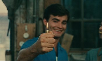 Movie still from “Happiness” (1965), directed by Agnès Varda – A young man holding a lit candle in his hand; Close Up shot, High angle
