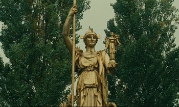 Movie still from “Happiness” (1965), directed by Agnès Varda – A statue of a woman holding a spear and holding a sword; Medium shot, Low angle