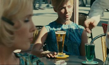 Movie still from “Happiness” (1965), directed by Agnès Varda – A woman sitting at a table with a glass of beer; Medium shot, Over the shoulder angle