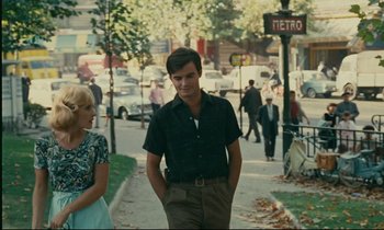 Movie still from “Happiness” (1965), directed by Agnès Varda – A man and a woman walking down a street; Medium shot, Over the shoulder angle
