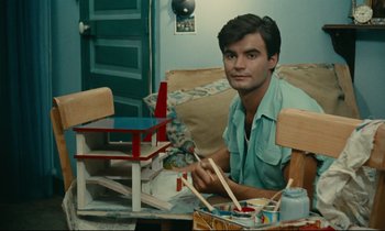 Movie still from “Happiness” (1965), directed by Agnès Varda – A man sitting in front of a wooden table; Medium shot, High angle